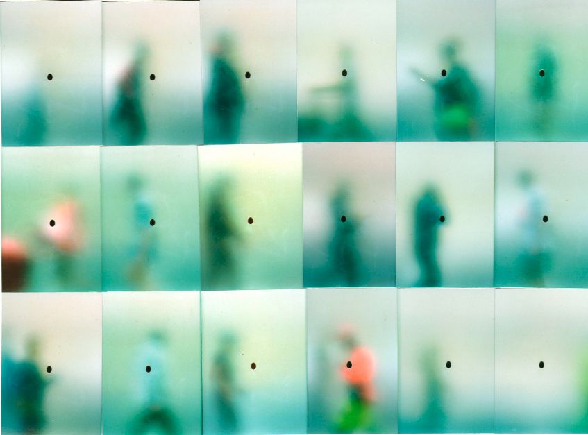 Grid of blurred, ghostlike figures walking past a translucent screen, each marked with a small dot, evoking repeated observation and pattern